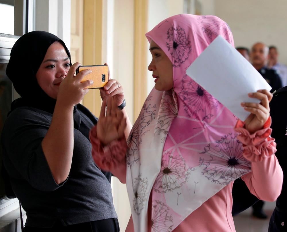Zarina Zainuddin (R) blocks a reporter from taking her picture, at the Petaling Jaya magistrate’s court, on Oct 2, 2019. — BBX-Images