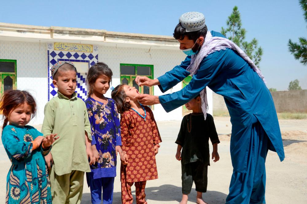 A health worker administers polio vaccine drops to a child during a polio vaccination campaign in Kandahar on May 23, 2022. AFPPIX