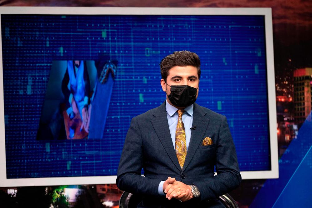 Seconds before he presents a news bulletin, Afghan television anchor Nisar Nabil puts on a black mask as a symbolic protest against the Taliban authorities for ordering women presenters to cover their faces on air. AFPPIX