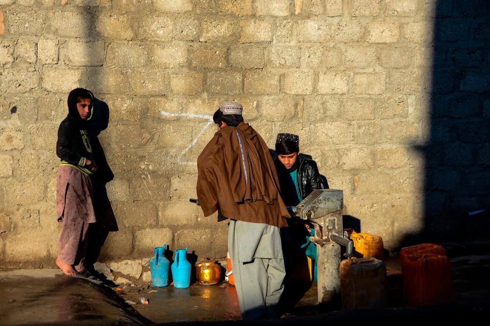 Afghan children use a hand-pump to fetch water along a street in Kandahar on February 21, 2022. AFPPIX