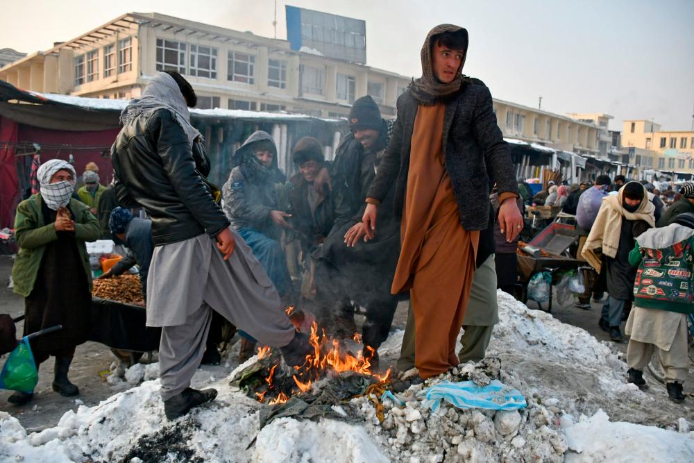 In this photograph taken on January 14, 2023, Afghan men warm themselves around a bonfire at a market in Mazar-i-Sharif/AFPPix