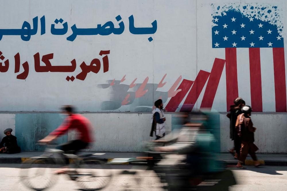 Taliban members walk past a mural depicting a US flag on the first anniversary of the withdrawal of US-led troops from Afghanistan, in Kabul on August 31, 2022. AFPPIX