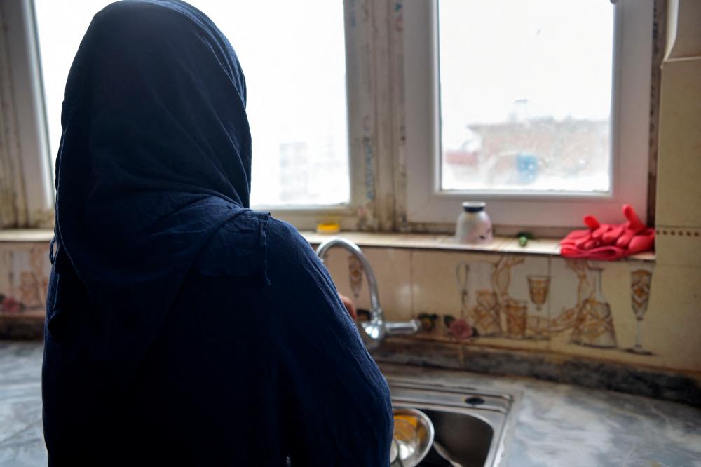 In this photo taken on February 1, 2023, Marwa, a divorced woman whose name has been changed for her protection, washes dishes during an interview with AFP at a house in an undisclosed location in Afghanistan. Abused for years by her ex-husband who broke all of her teeth, Marwa has retreated into hiding with her eight children after Taliban commanders tore up her divorce/AFPPix