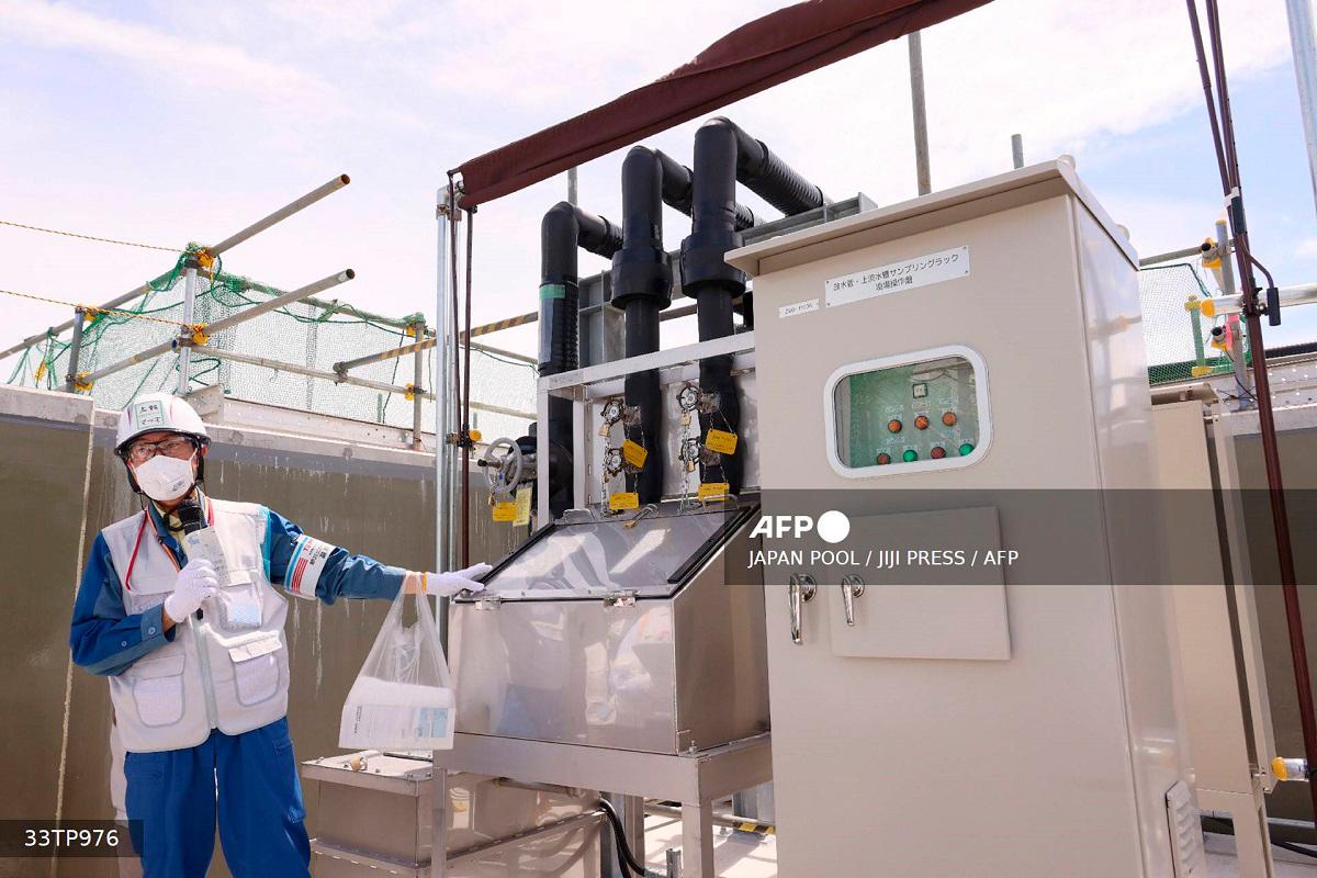 An official demonstrates an equipment for sampling water to analyze the concentration of radioactive tritium before discharging diluted treated water, as part of the facility for the releasing the treated water of the Tokyo Electric Power Company Holdings Inc. (TEPCO) Fukushima Daiichi Nuclear Power Plant in Okuma, Fukushima prefecture on August 27, 2023. - JAPAN POOL / JIJI PRESS / AFP