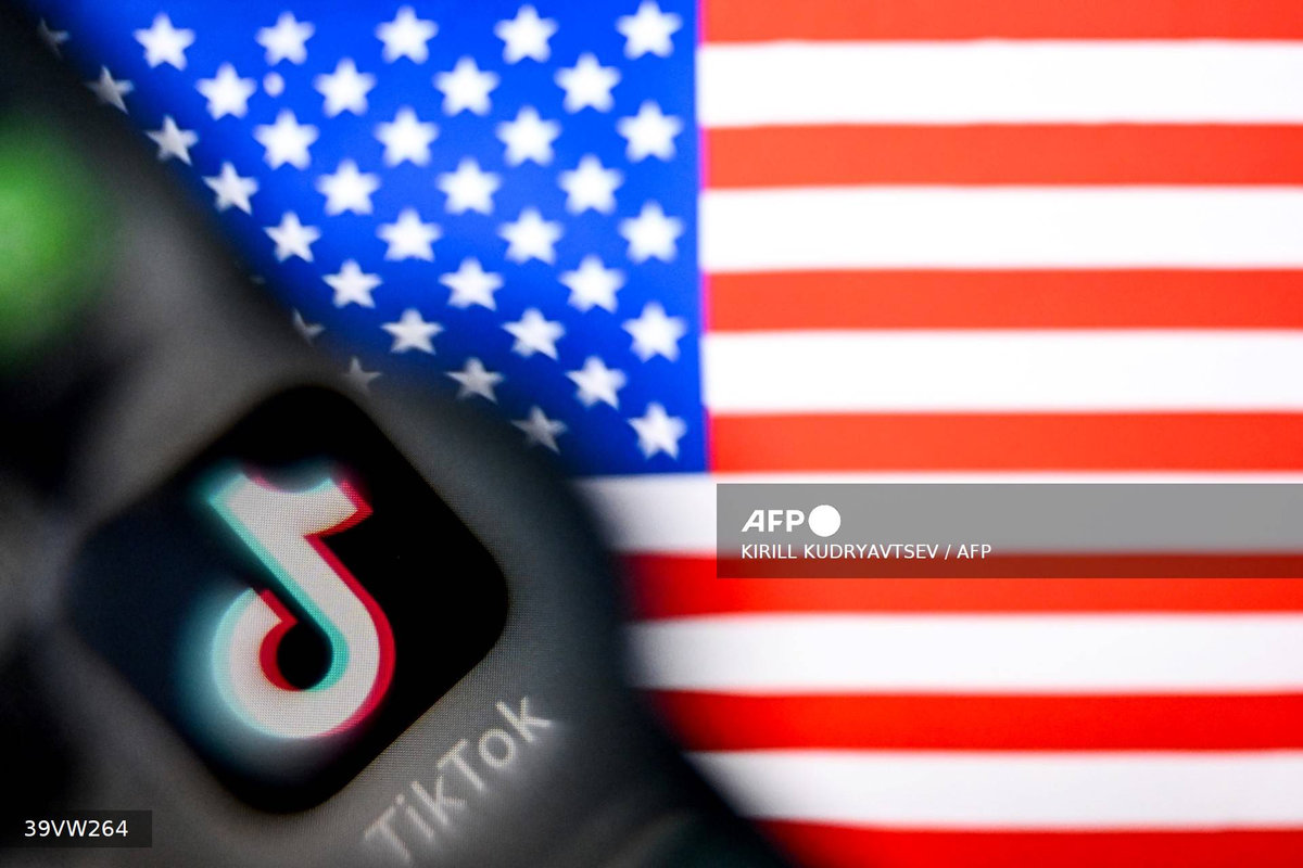 A photo taken on April 10, 2025 shows the Chinese social networking service TikTok's logo on a smartphone screen (L) and US' flag illustration on a laptop screen in Frankfurt am Main, western Germany. US President Donald Trump said on April 6, 2025 that China would have agreed to a deal on the sale of TikTok if it were not for the tariffs imposed by Washington on Beijing last week. (Photo by Kirill KUDRYAVTSEV / AFP)