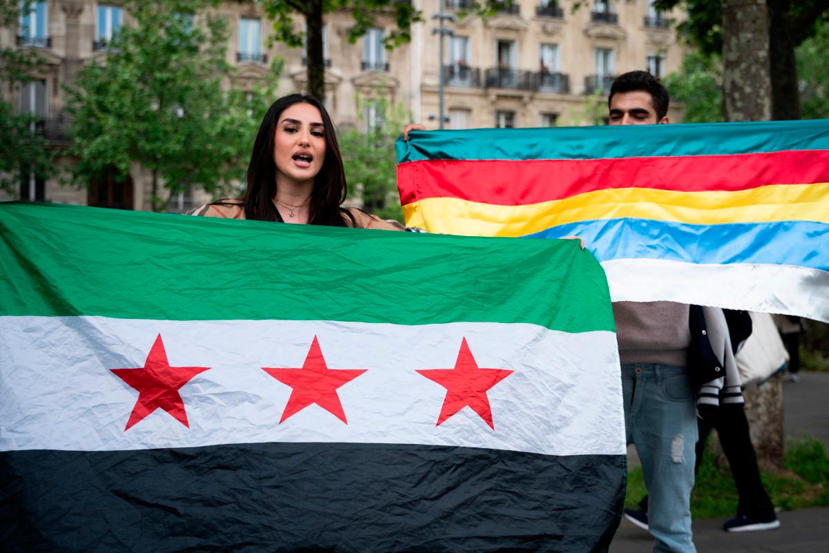 A woman holding the flag of Syria takes part in a demonstration at Place de la République organised by Kurd, Alawite and Druze minority groups of Syria, protesting the visit of Syria’s interim President,in Paris on May 7, 2025. (Photo by LEO VIGNAL / AFP)