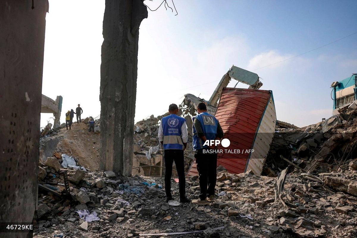 UN workers stand amid the rubble of an UNRWA aid supply depot and shelter, heavily damaged in an overnight Israeli strike in Jabalia in the northern Gaza Strip on May 10, 2025. - BASHAR TALEB / AFP