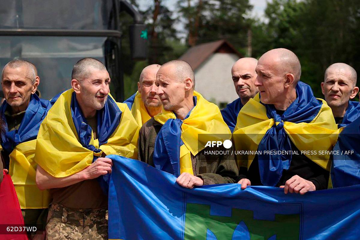 This handout photograph taken and released by the Ukrainian Presidential Press Service on June 14, 2025, shows Ukrainian prisoners of war (POWs) wrapped with Ukrainian national flags posing for a photograph following an exchange of prisoners. - AFP PHOTO / UKRAINIAN PRESIDENTIAL PRESS SERVICE