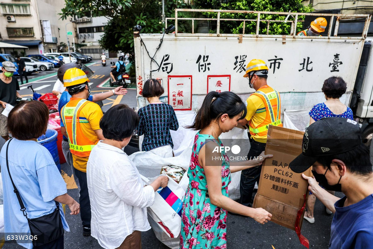 This photo taken on June 19, 2025 shows residents folding cardboard boxes for recycling next to a collection truck in Taipei. Taiwanese residents holding plastic bags of rubbish stand on a footpath as a yellow garbage truck playing classical music over a loudspeaker pulls up. For decades, the tinkling of Beethoven's Fur Elise or Tekla Badarzewska-Baranowska's Maiden's Prayer has alerted Taiwanese households to take out their garbage. -AFP