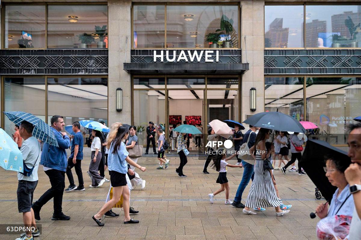 For representational purposes only: People walk past the Huawei Shanghai flagship store in the Huangpu district in Shanghai, on June 23, 2025. (Photo by Hector RETAMAL / AFP)