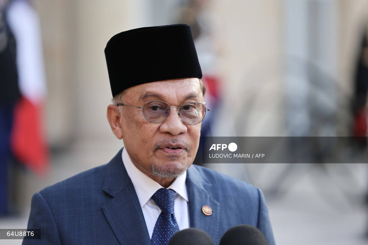 Malaysia's Prime Minister Anwar Ibrahim speaks next to France's President Emmanuel Macron during a joint press statement prior to a working dinner at the Elysee Palace in Paris on July 4, 2025. - AFP