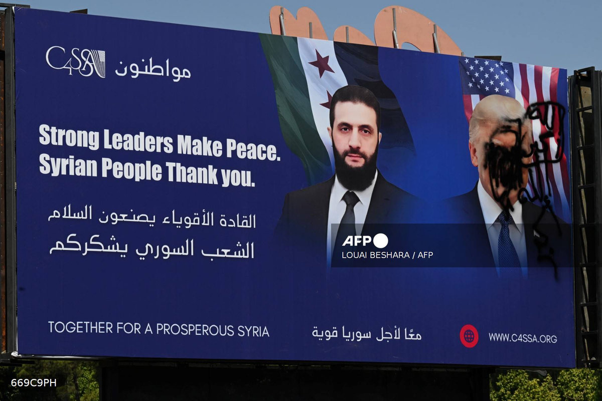 A picture shows a promotional poster bearing the portrait of Syria’s interim President Ahmad al-Sharaa and a defaced portrait of US President Donald Trump in the capital Damascus on July 9, 2025. - AFP