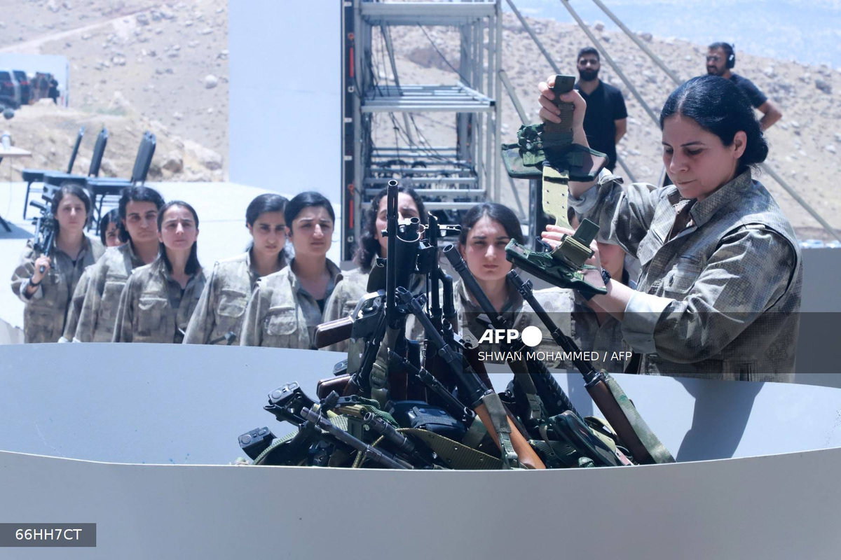 Fighters with the Kurdistan Workers’ Party (PKK) line up to put their weapons into a pit during a ceremony in Sulaimaniyah, in Iraq’s autonomous Kurdistan region, on July 11, 2025. - AFP