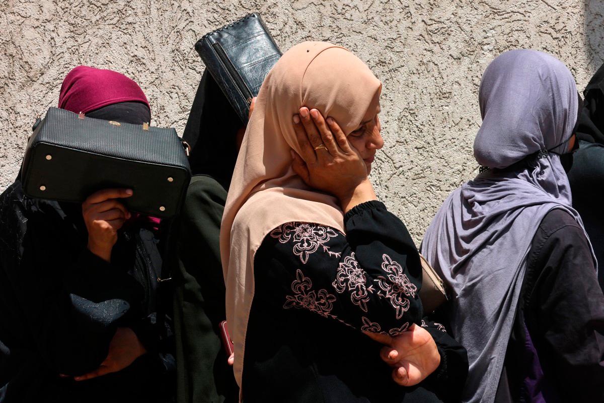 Palestinian women line up to receive bags of flour at a UN World Food Programme (WFP) warehouse on Al-Jalaa street in Gaza City, in the northern Gaza Strip on July 12, 2025. (Photo by Omar AL-QATTAA / AFP)