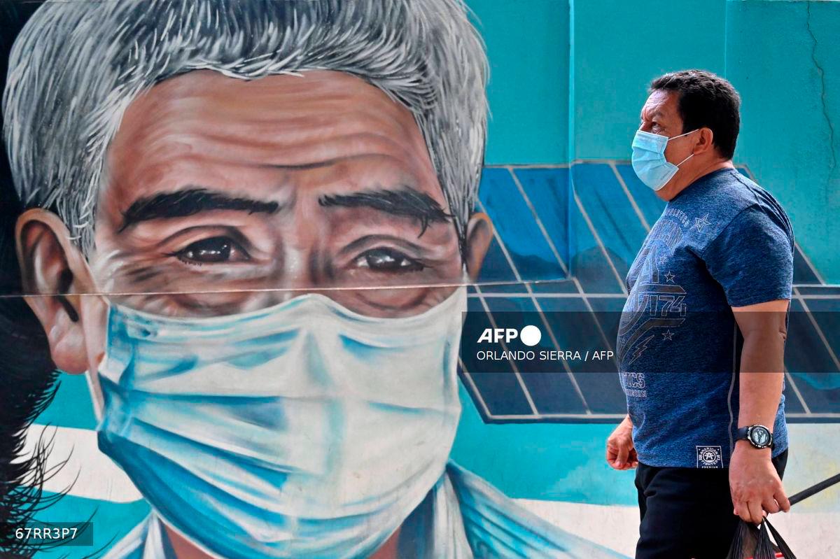A man wears a surgical mask as he walks down an avenue in Tegucigalpa on July 24, 2025. - AFP