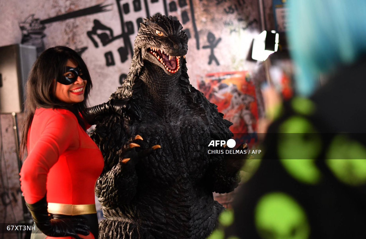 An attendee poses for photos with Godzilla during Comic-Con International in San Diego, California, on July 26, 2025. - AFP