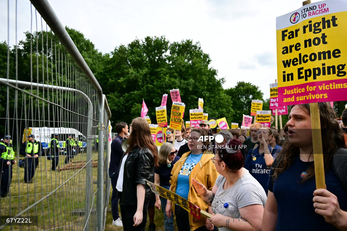 Protestors hold placards reading Far right are not welcome in Epping as they face an anti-immigrant demonstration in front of The Bell Hotel believed to be housing asylum seekers, in Epping, northest of London, on July 27, 2025. - AFP