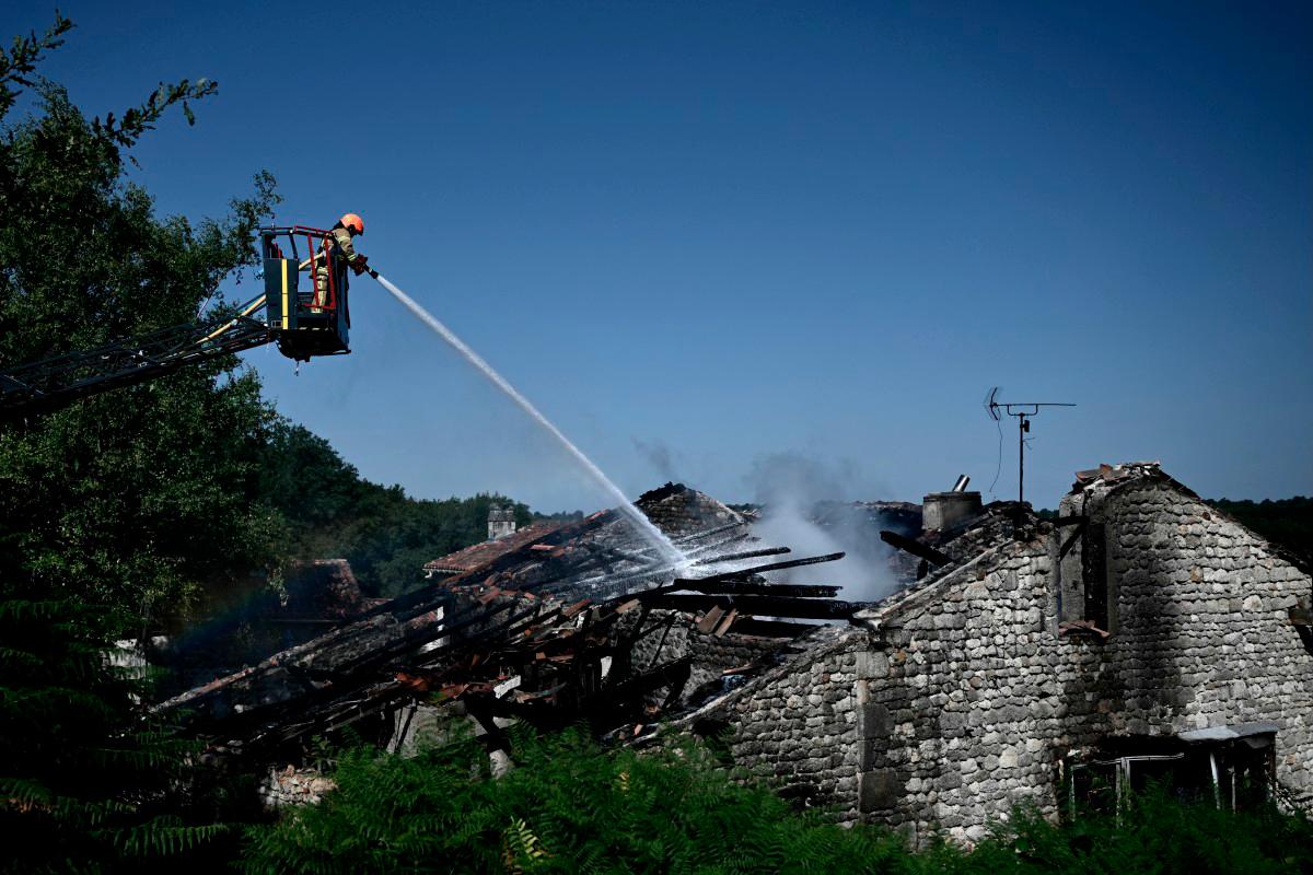 A firefighter works at the site of a French holiday cottage gite for disabled adults where a fire broke out leaving one person dead and four people still missing in Montmoreau, south-western France, on July 28, 2025. (Photo by Philippe LOPEZ / AFP)