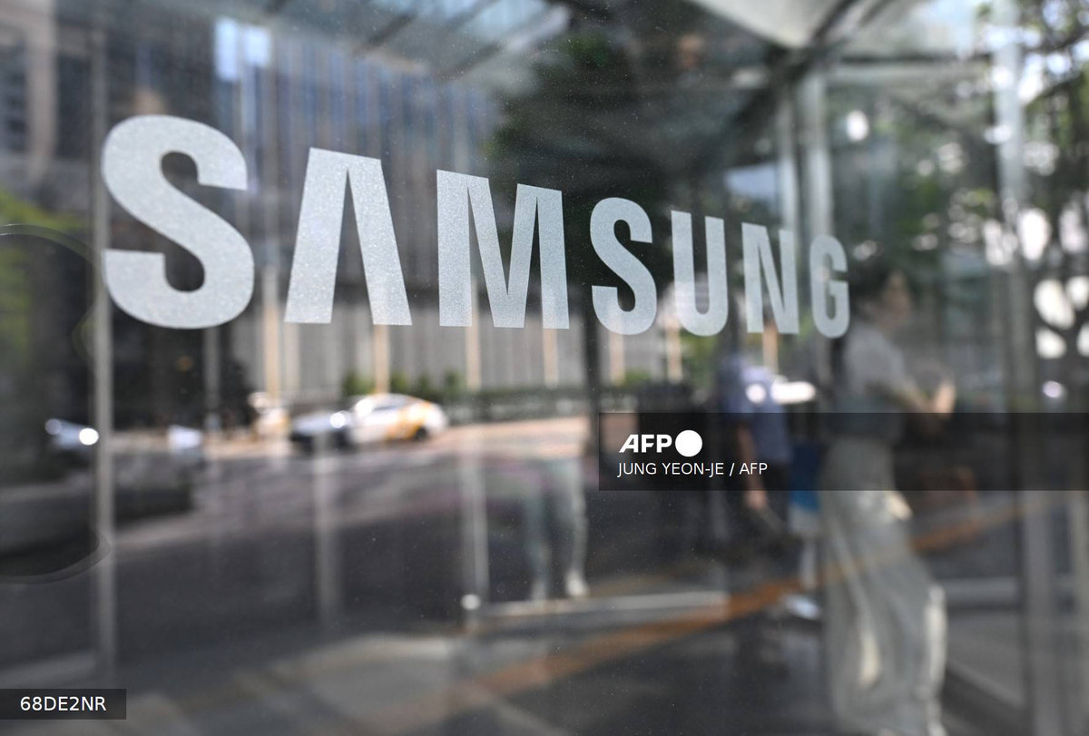 A woman walks past a logo of Samsung Electronics displayed on a glass door at the company's Seocho building in Seoul on July 8, 2025. - AFP
