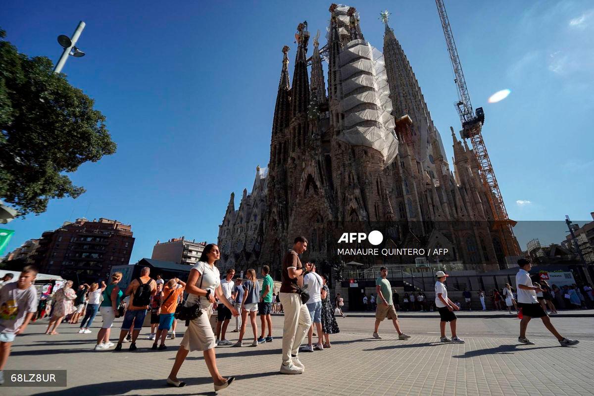 Tourists walk past the Sagrada Familia basilica in Barcelona, on August 2, 2025. (Photo by Manaure QUINTERO / AFP)