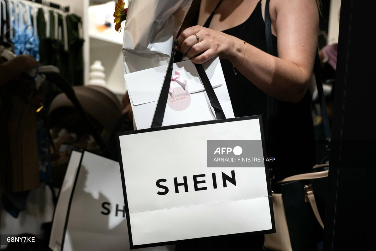 (FILES) A customer holds her bags as she leaves a pop-up store of the Chinese-founded fast fashion brand Shein, in Dijon on June 26, 2025. Italy's competition watchdog said on August 4, 2025, it has fined the company responsible for Shein's websites in Europe one million euros ($1.15 million) for false and confusing claims about the e-commerce giant's efforts to be environmentally green. (Photo by ARNAUD FINISTRE / AFP)