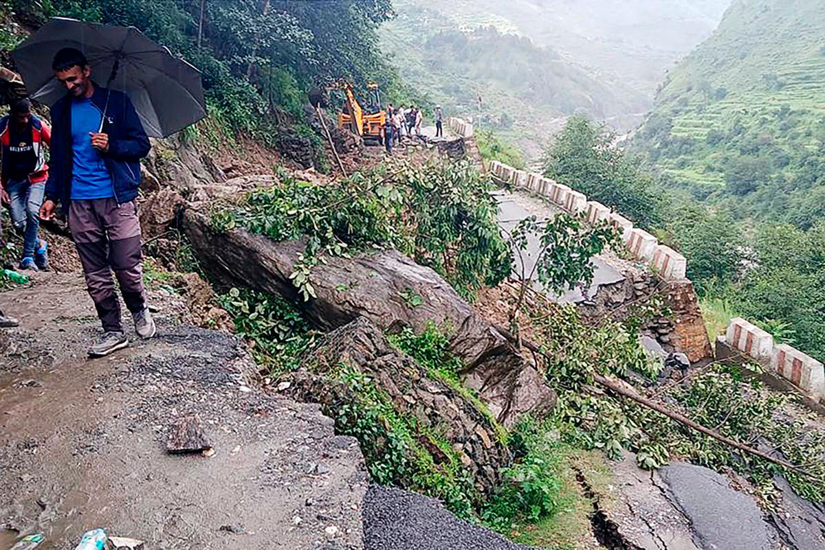 People stand beside a damaged road at a village near Uttarkashi on August 6, 2025, a day after a cloudburst caused a massive mudslide and flash floods in India’s Uttarakhand state. (Photo by AFP)