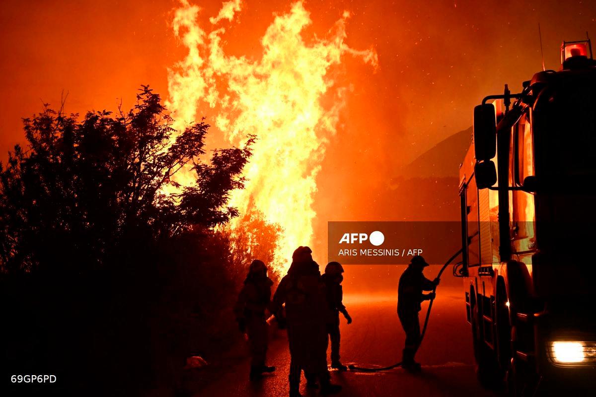 Firefighters work to extinguish a wildfire near the city of Patras, western Greece on August 13, 2025. Greece on August 13, 2025 battled to contain more than 20 wildfires including one menacing its third-largest city Patras as a heatwave stoked blazes and forced the evacuation of thousands in southern Europe -Photo by Aris MESSINIS / AFP
