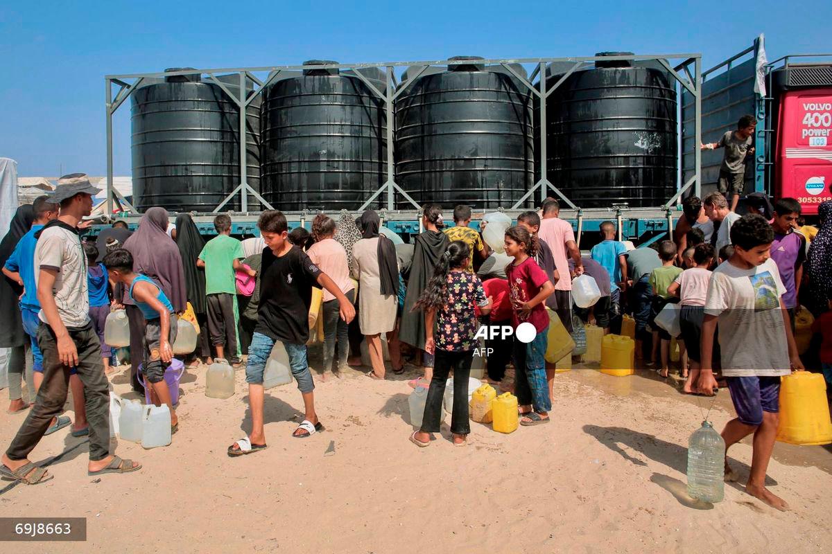 Displaced Palestinians attempt to fill water tanks in the Mawasi area of Khan Yunis, on August 14, 2025, as international organisations have been working to provide people with clean water amid the worsening crisis and the spread of diseases due to poor sanitation in the Gaza Strip. - AFP