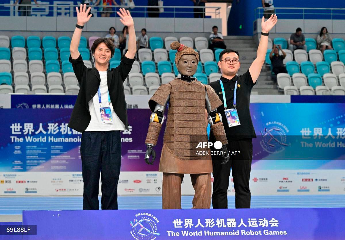 Winner of the dance event from Beijing Dance Academy and Hubei Optics Valley Dongzhi celebrates during the award ceremony at the World Humanoid Robot Games in Beijing on August 15, 2025. - AFP