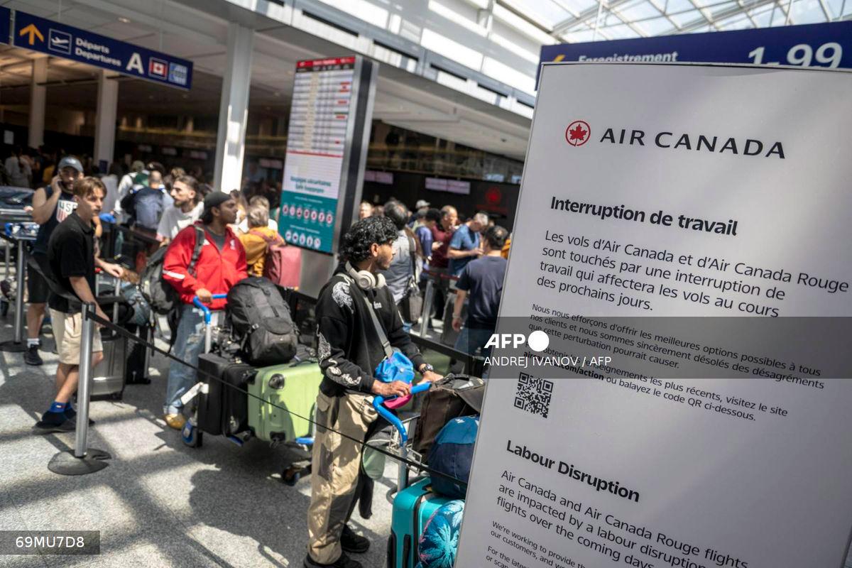 Passengers wait in line to speak to Air Canada representatives to see if they can reschedule flights at the Pierre-Elliott Trudeau Airport in Montreal, Quebec, Canada, on August 15, 2025. - AFP