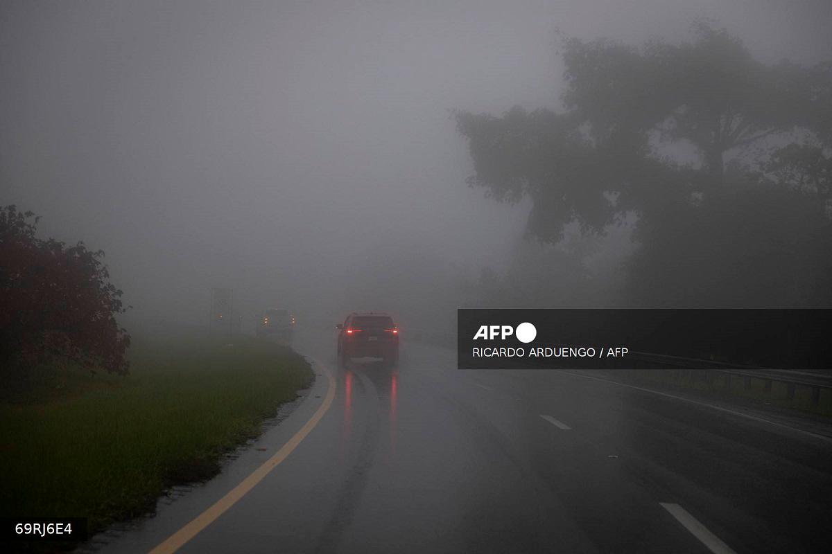 Car drive through heavy fog as category 3 Hurricane Erin leaves the region in Cayey, Puerto Rico on August 16, 2025. - Ricardo ARDUENGO / AFP