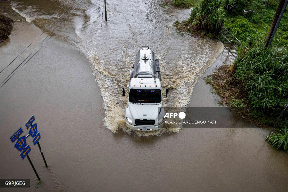 A truck drives through a flooded road as category 3 Hurricane Erin leaves the region in Naguabo, Puerto Rico on August 16, 2025. (Photo by Ricardo ARDUENGO / AFP)
