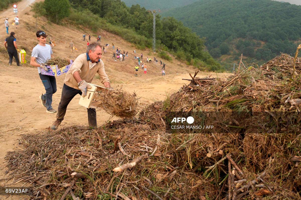 People carry out mountain clearing work in anticipation of the possible arrival of the fire from the Picos de Europa National Park blaze, in the town of Riano, Leon province, Spain on August 18, 2025. - CESAR MANSO / AFP
