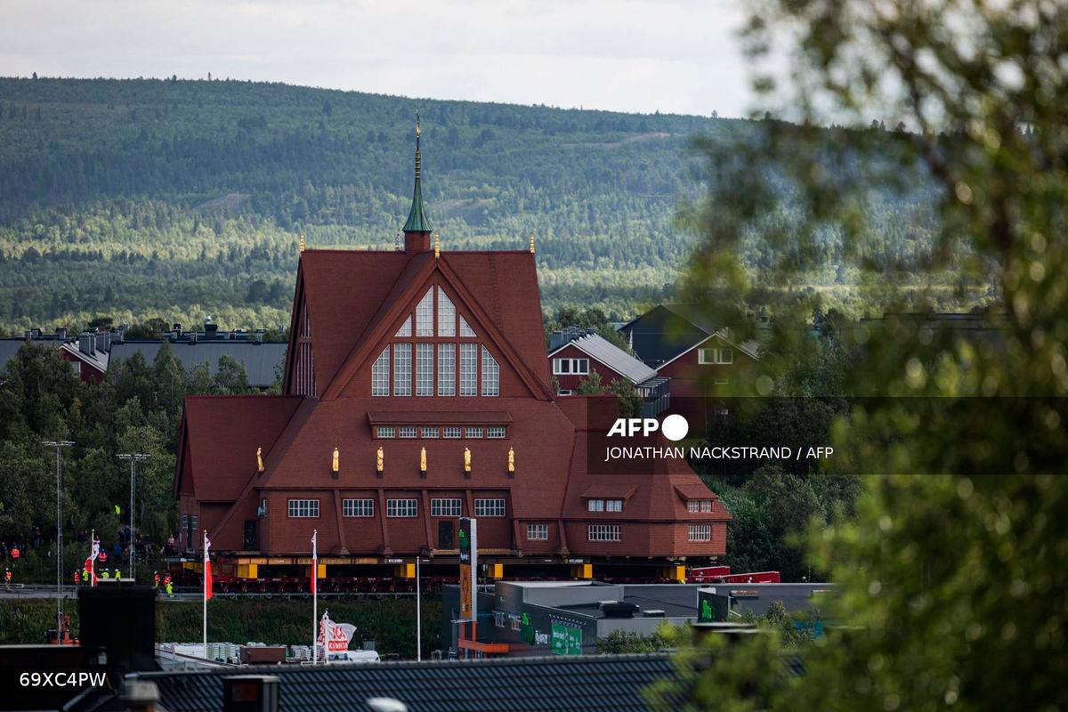 The wooden Kiruna Church is seen in the background as it is being transferred to its new location, in Kiruna, Sweden on August 19, 2025. (Photo by Jonathan NACKSTRAND / AFP)