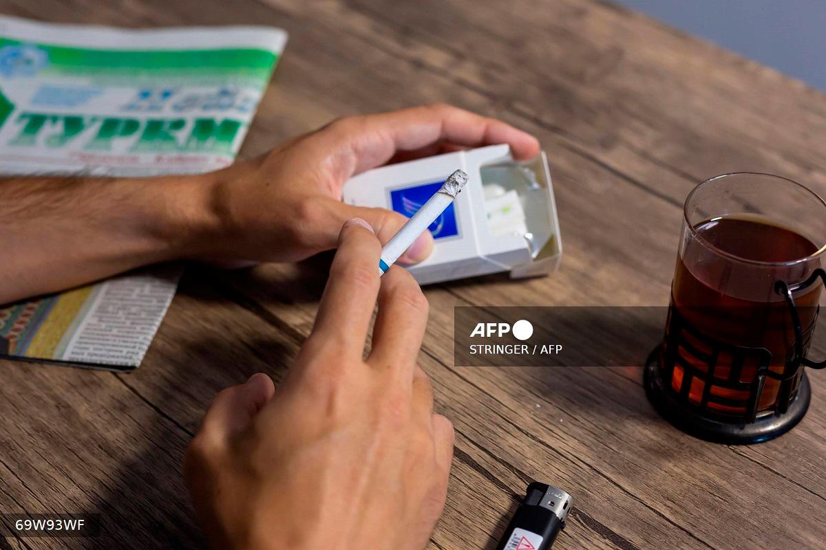 A man smokes in his appartment on July 27, 2025, as Turkmenistan imposes smoking restrictions. - STRINGER / AFP