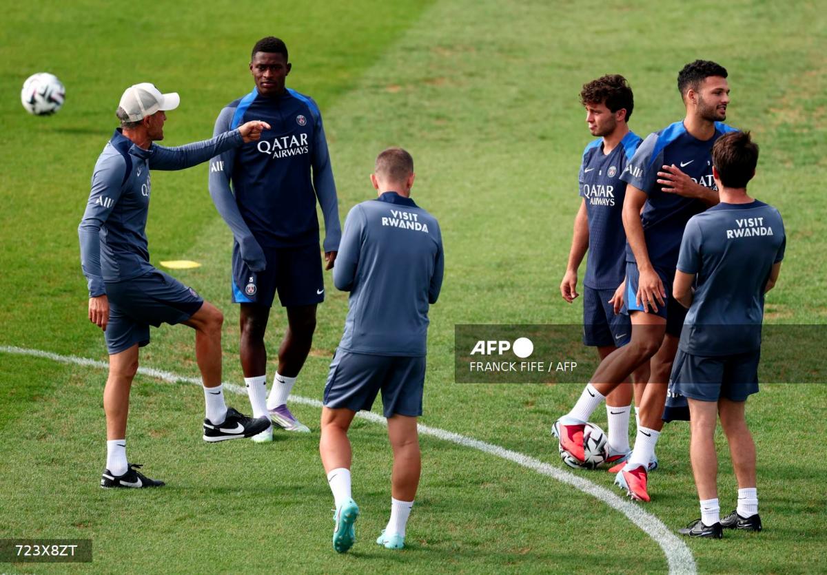 Paris Saint-Germain's Spanish headcoach Luis Enrique (L) speaks with Paris Saint-Germain's Portuguese defender #25 Nuno Mendes (2ndL) during a training session at French L1 Paris Saint-Germain (PSG) football club's training ground at Poissy, north-west of Paris on August 21, 2025, on the eve of the L1 football match PSG against SCO Angers. - AFPPIX