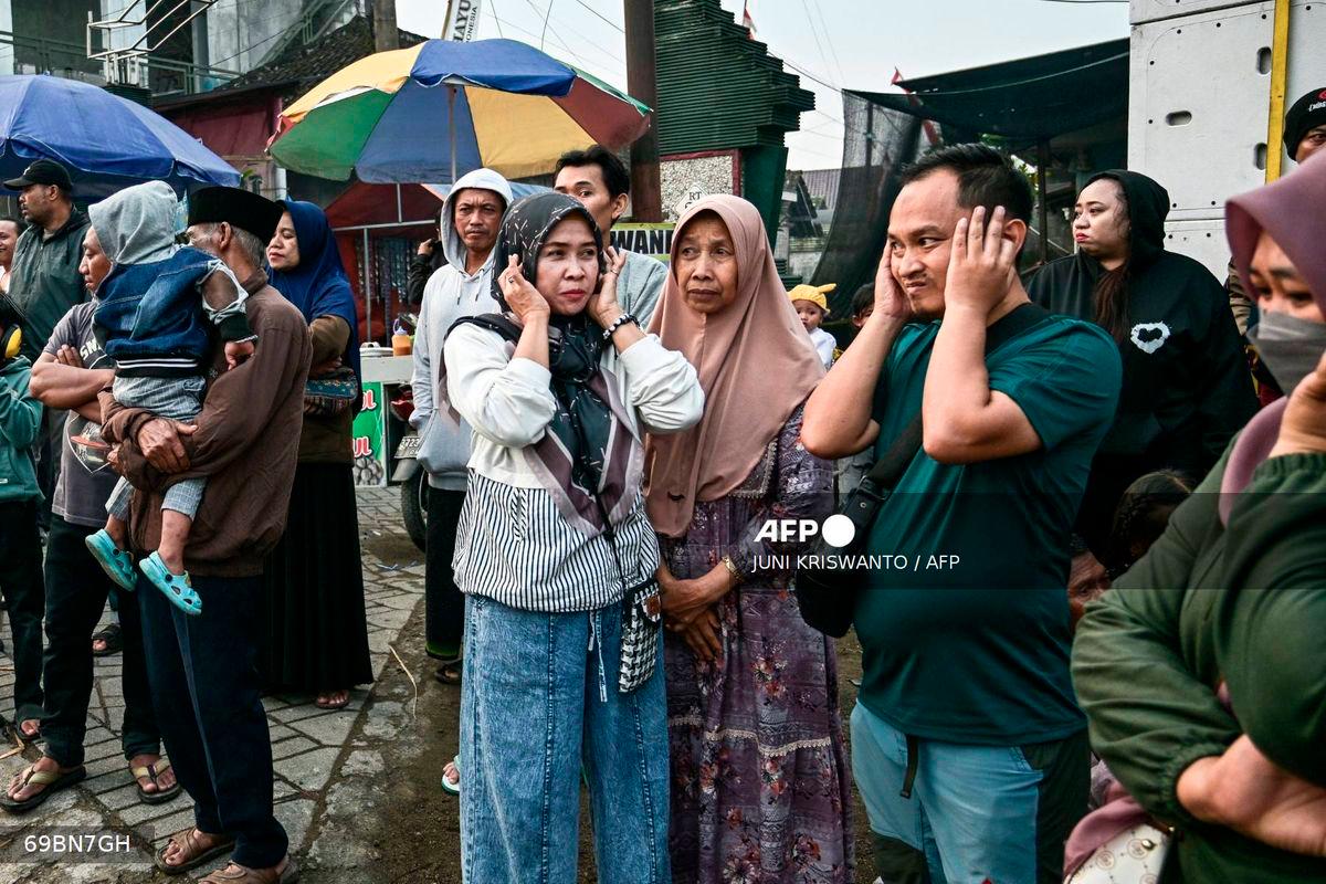 This photo taken on August 9, 2025 shows people covering their ears as a truck mounted with a tower of subwoofers drives past during a sound horeg, which loosely means to move or vibrate in Javanese, held as part of Indonesia's 80th Independence Day celebrations in Malang, East Java. - AFP