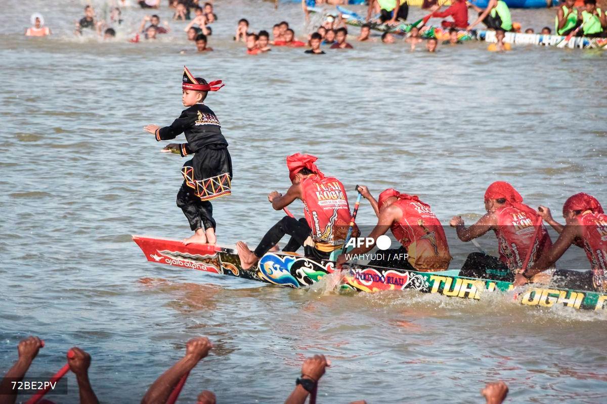 Rayyan Arkan Dikha (L), an 11-year-old boy who went viral for his calm dance on the bow of a traditional longboat, performs during the Pacu Jalur longboat race festival on the Kuantan River in Kuantan Singingi Regency, Riau Province, on August 22, 2025. - AFP