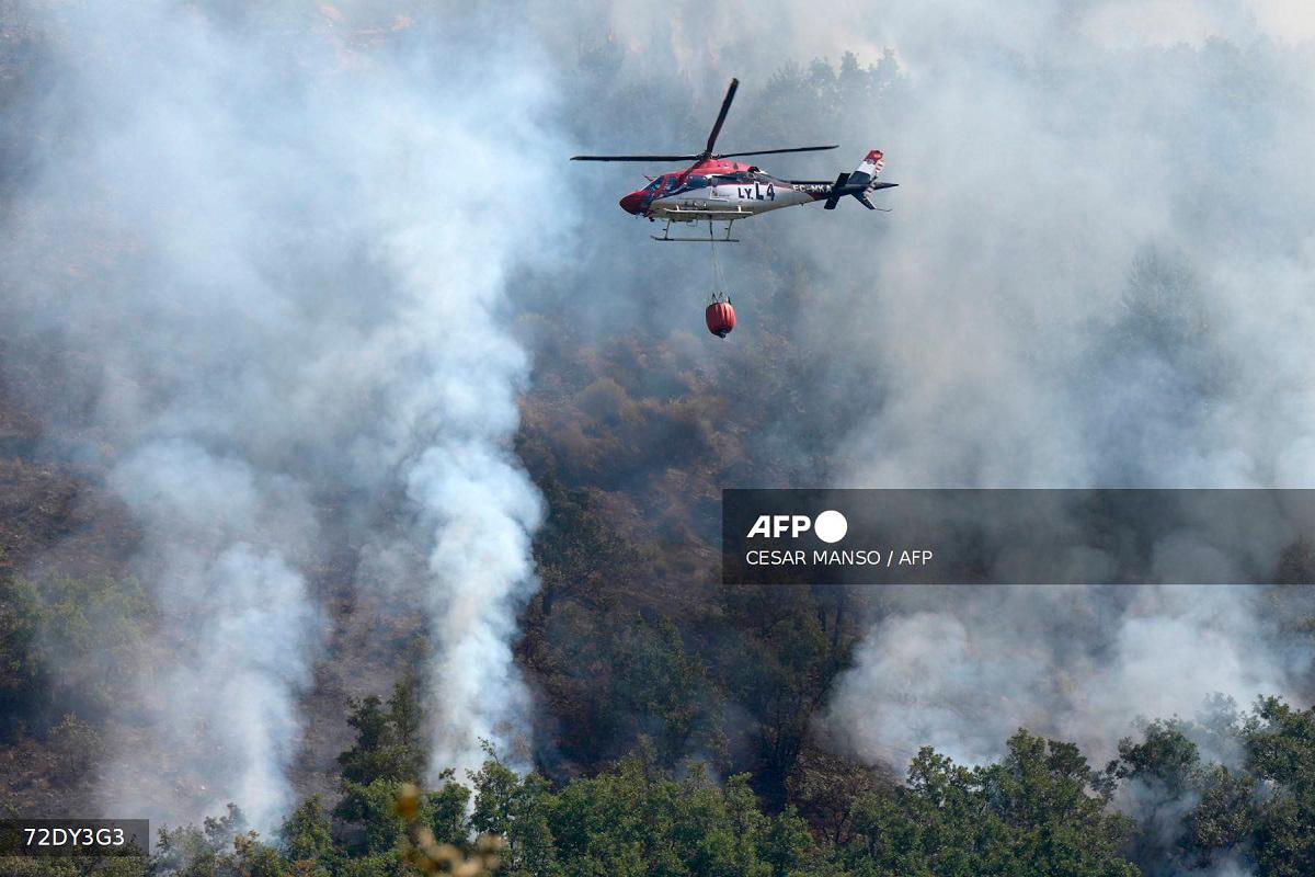 A firefighter helicopter flies above a wildfire in Garano, near Leon, northwestern Spain, on August 25, 2025. - Cesar MANSO / AFP
