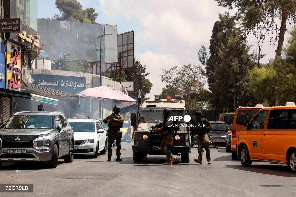 Israeli soldiers block a road during a raid in the city of Ramallah, in the Israeli occupied West Bank, on August 26, 2025. (Photo by Zain JAAFAR / AFP)