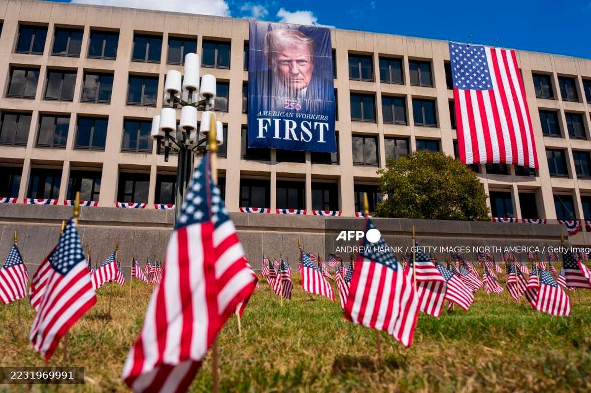 Hundreds of small American flags stick out of the lawn and a photo of U.S. President Donald Trump is displayed on the side of the U.S. Department of Labor on August 29, 2025 in Washington, DC. Andrew Harnik/Getty Images/AFP (Photo by Andrew Harnik / GETTY IMAGES NORTH AMERICA / Getty Images via AFP)