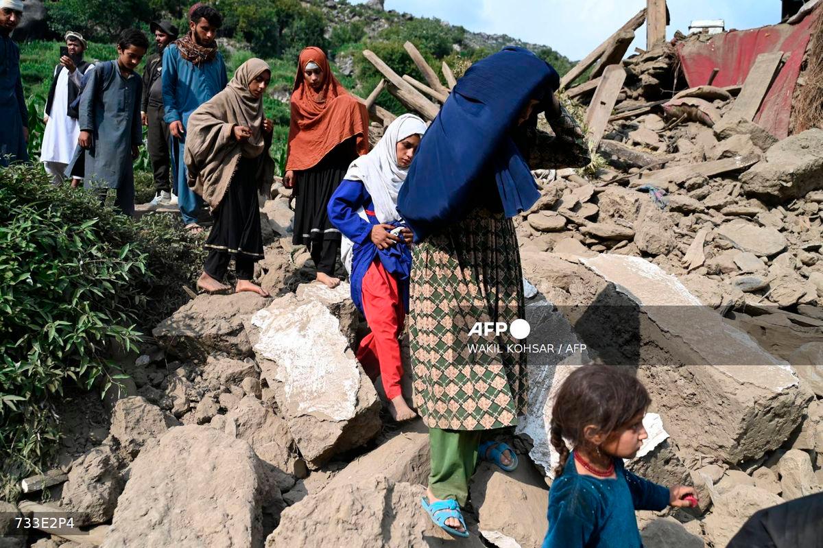 Afghan men and women walk past a damaged house following earthquakes in the Mazar Dara village of Nurgal, a district of the Kunar Province, in Eastern Afghanistan, on September 1, 2025. (Photo by Wakil Kohsar / AFP)