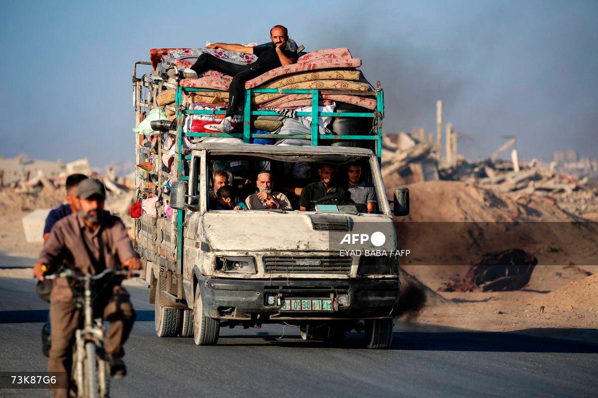 Palestinians fleeing south, ride a truck with their belongings, on the coastal road near the Nuseirat refugee camp in the central Gaza Strip, on August 5, 2025. - AFP