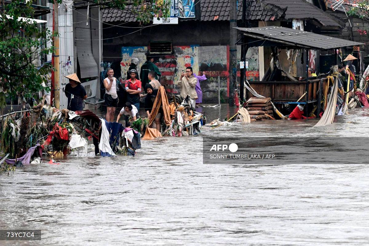 Flood-affected residents look on and clear debris in their neighbourhood following heavy rainfall in Denpasar, Indonesia's Bali island, on September 10, 2025. - AFP