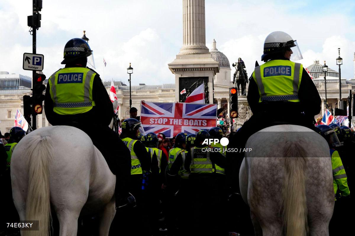 Mounted police officers look on as a Union Jack flag is displayed by supporters of British far-right activist Tommy Robinson whose real name is Stephen Yaxley-Lennon, during a ‘Free speech’ march, in central London on September 13, 2025. (Photo by CARLOS JASSO / AFP)