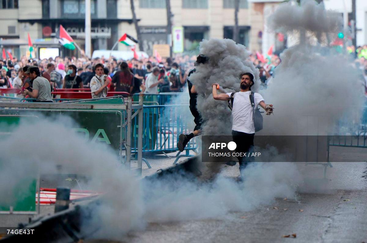 A man throws back to police a tear gas canister after Pro-Palestinians protestors invaded the street during the 21st and last stage of the Vuelta a Espana 2025, in Madrid on September 14, 2025. - AFP