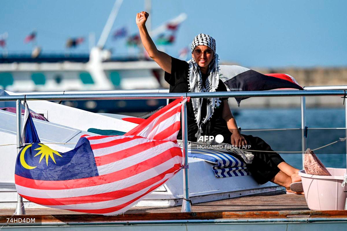 A woman gestures as she rides aboard a vessel with other activists and human rights defenders, departing from Tunisia's northern port of Bizerte, on September 14, 2025 to join the last boats taking part in the Global Sumud Flotilla, bound for the Gaza Strip to break Israel's blockade on the Palestinian territory. - AFP