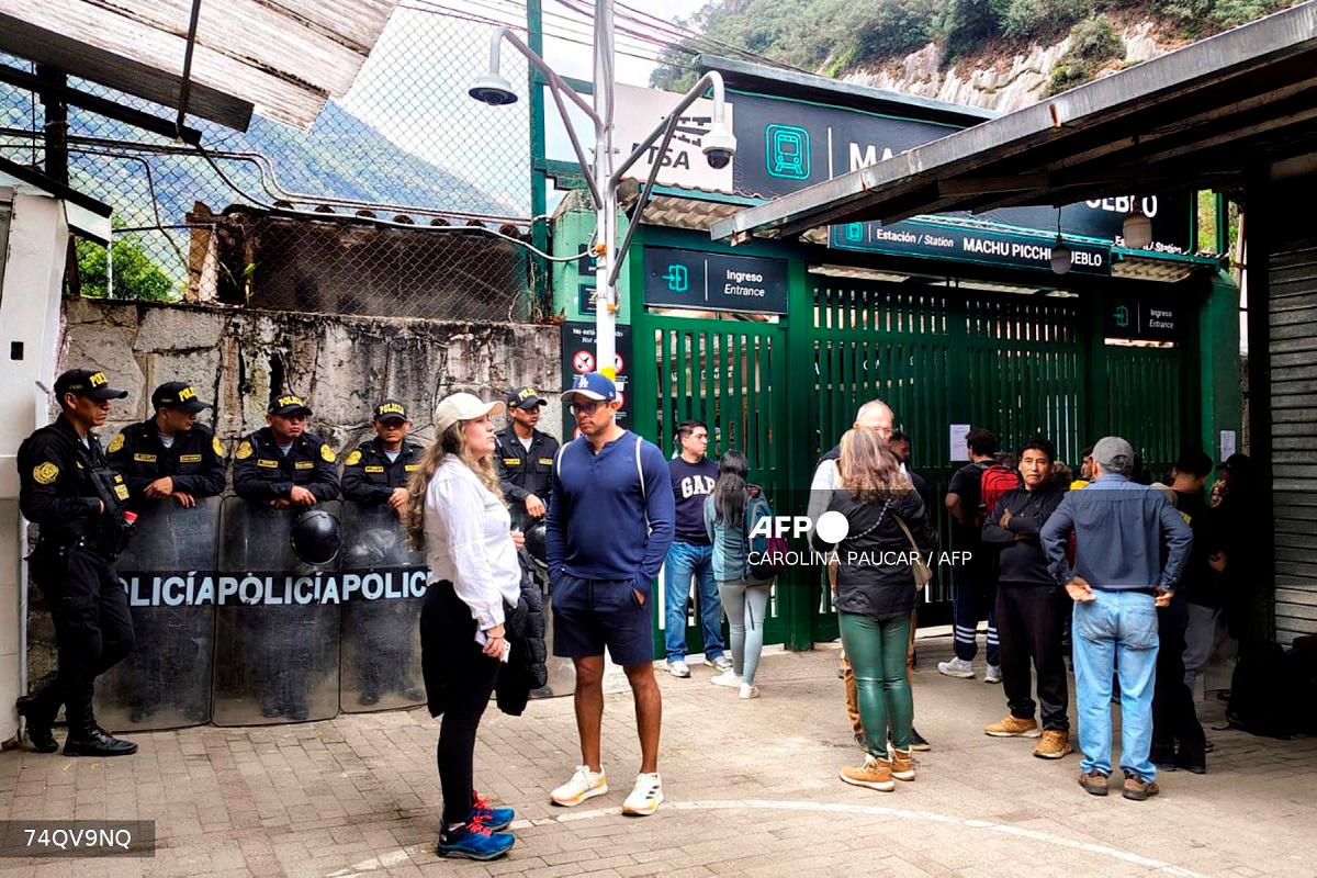 Police officers stand guard next to a group of tourists at the train station in Machu Picchu Pueblo, Peru, on September 16, 2025. - Carolina Paucar / AFP
