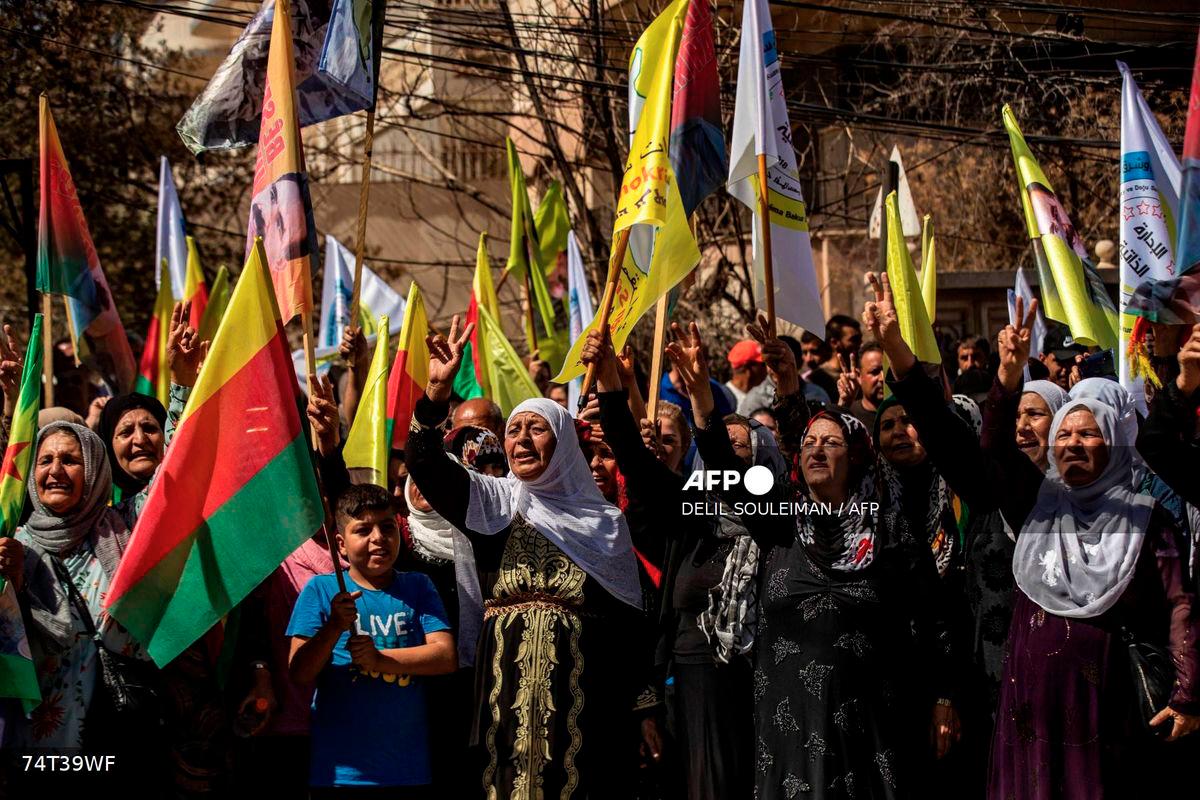 Syrian Kurds lift placards and flags during a rally calling for an autonomous administration and Kurdish rights in Syria's predominantly-Kurdish northeastern city of Qamishli on September 17, 2025. - AFP