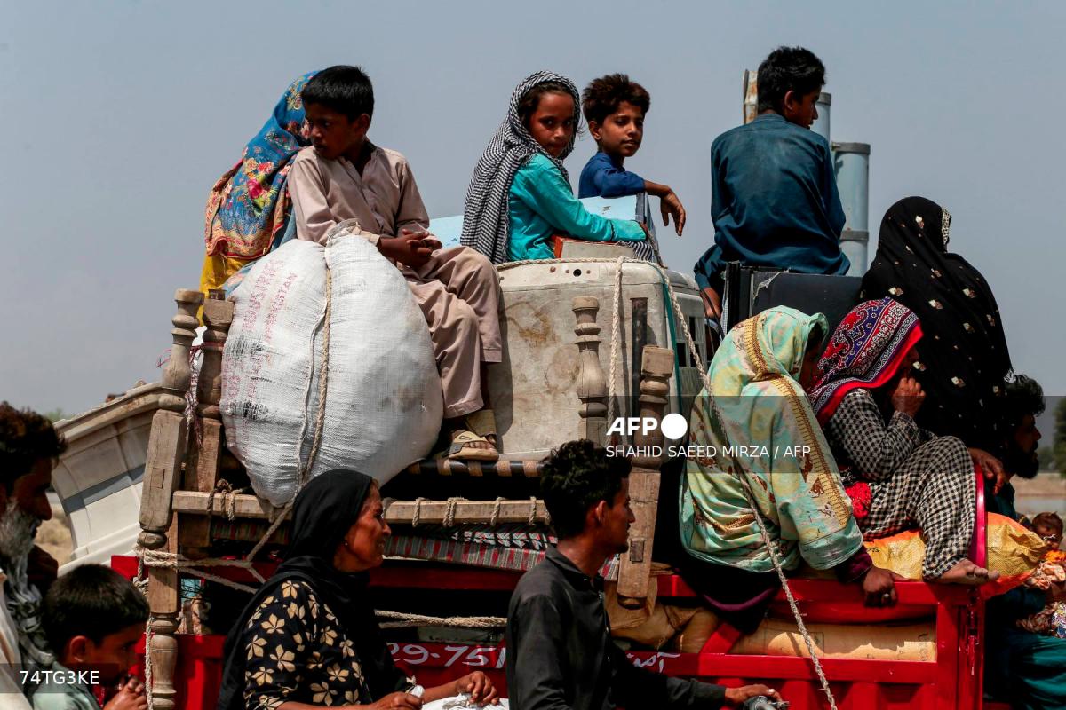 Flood-affected villagers carrying belongings arrive on a tractor near a closed motorway damaged by floodwater at Jalalpur Pirwala, in the Multan district of Punjab province, on September 17, 2025, after the Chenab River overflowed following heavy monsoon rains. - AFPPIX